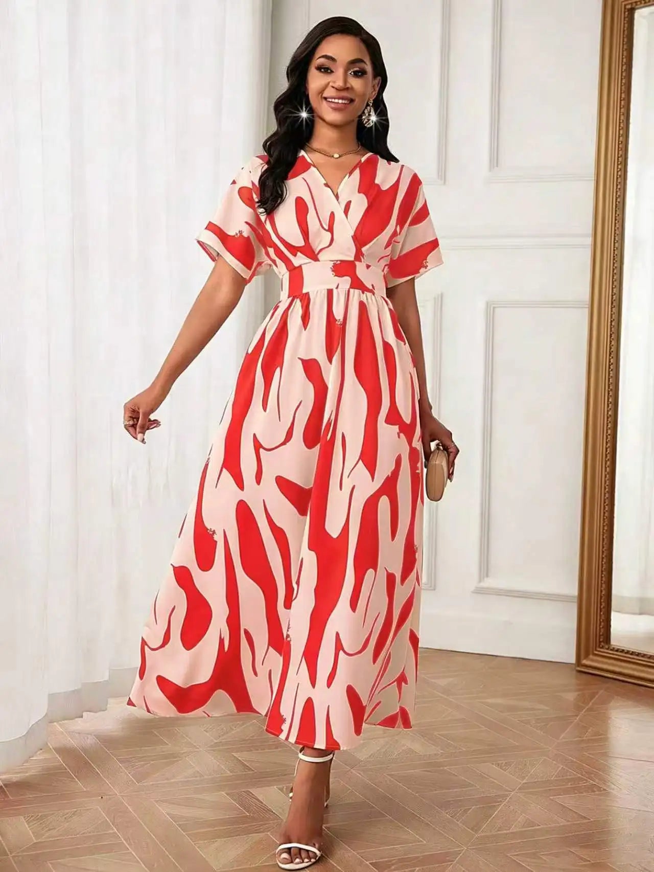 A woman models a short-sleeve midi dress with a red and cream abstract pattern, standing in an elegant room with white paneled walls and a wooden floor.