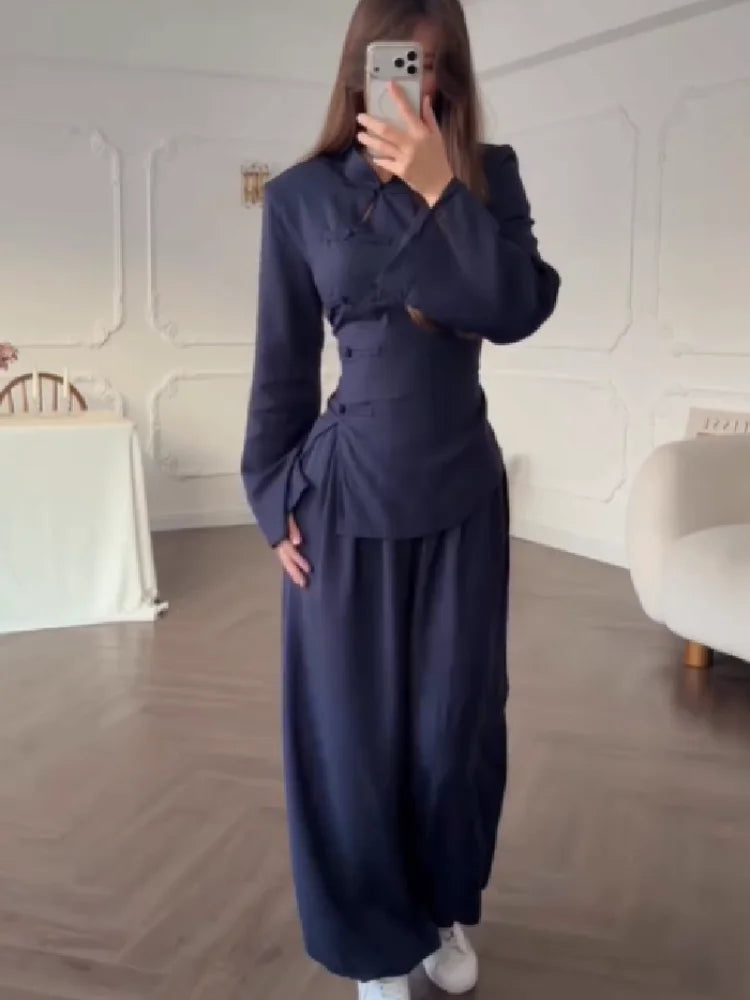 Person wearing a navy blue outfit in a room with white walls and wooden floor.
