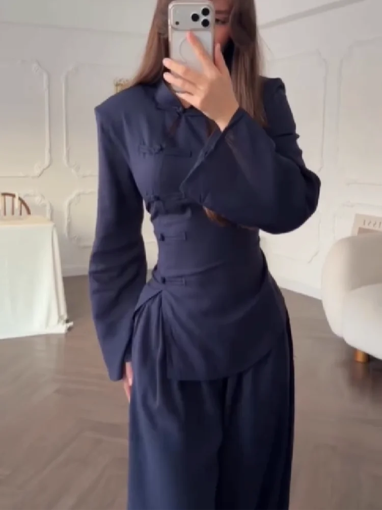 Person wearing a navy blue outfit in a room with white walls and wooden floor.