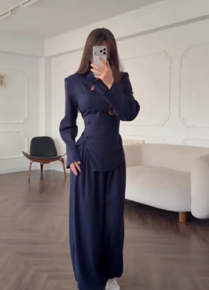 Person wearing a navy blue suit taking a mirror selfie in an elegant room.