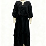 A black long-sleeve maxi dress with a wrap-style V-neckline, tassel tie details, and a tiered ruffled hem, displayed on a cream-colored dress form mannequin against a white background.