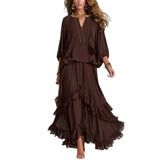 A woman modeling a dark brown bohemian-style two-piece set consisting of a loose long-sleeve top and a tiered ruffled maxi skirt, shown against a plain white background.