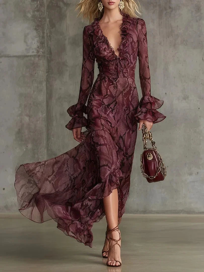 Woman wearing a burgundy lace dress with ruffled sleeves against a gray concrete wall.