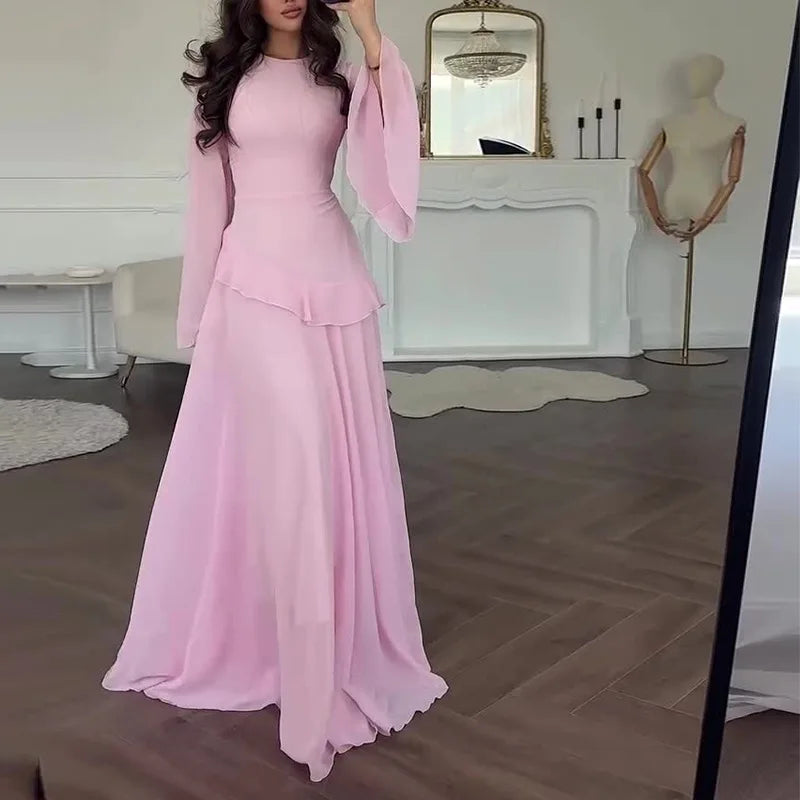 Woman in a pink dress standing in a room with a mirror and decor.