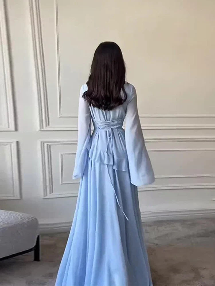 Woman wearing a light blue dress with long sleeves in an elegant room.