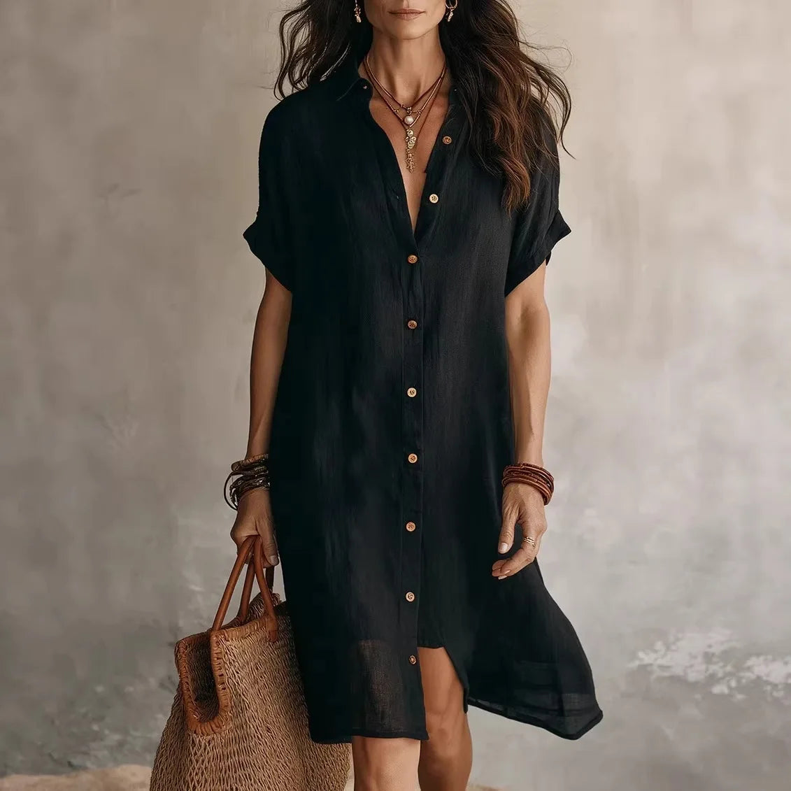 Woman wearing a black dress holding a woven bag against a neutral background
