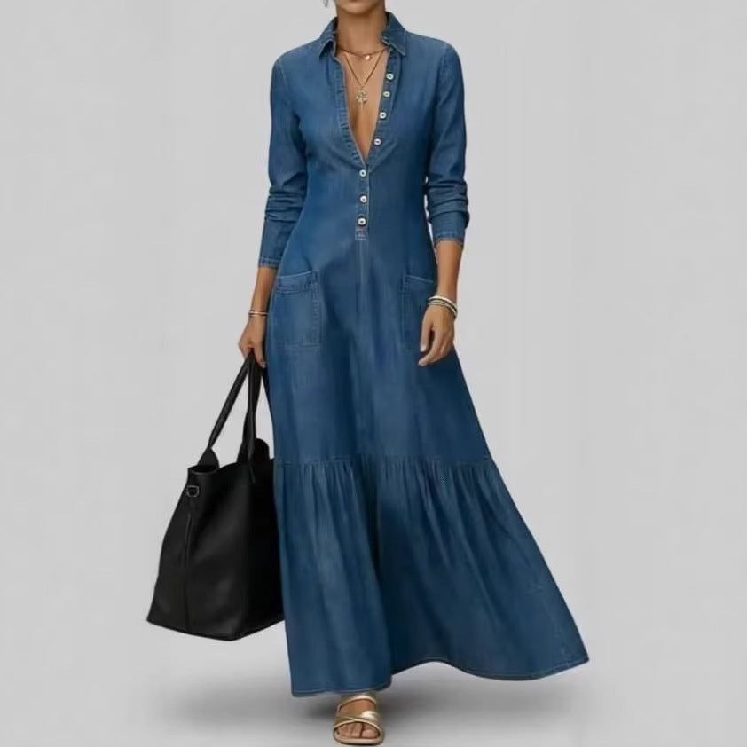Woman wearing a long blue denim dress holding a black handbag on a gray background