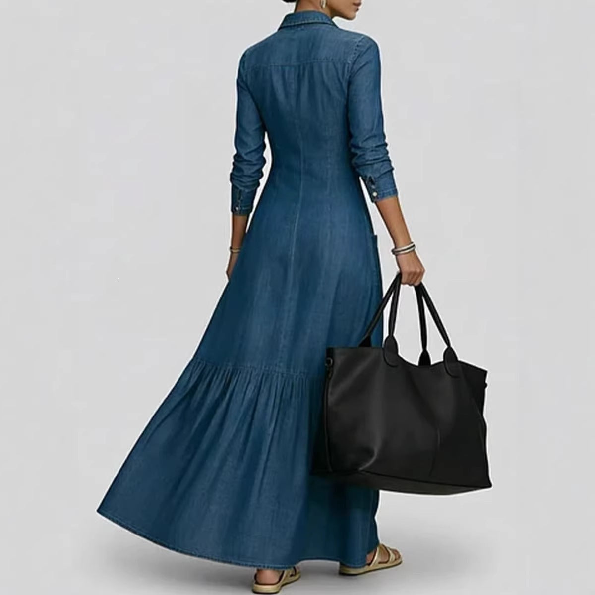 Person wearing a long blue dress holding a black bag on a plain background