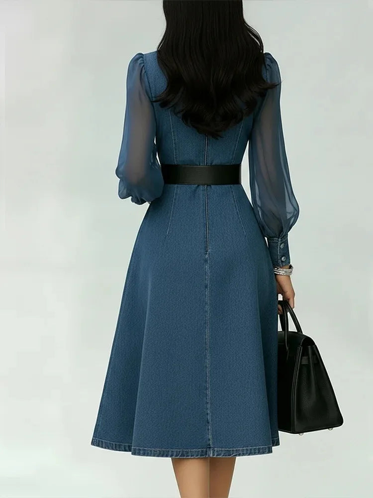 Woman wearing a blue dress with sheer sleeves against a white background