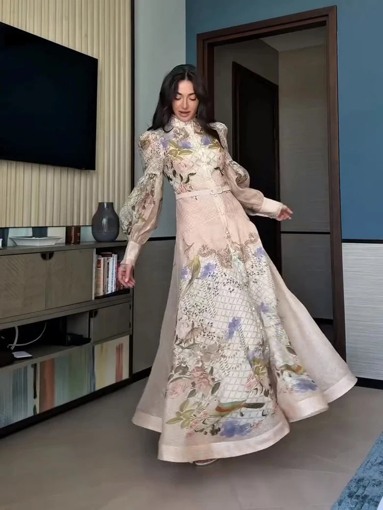 Woman in a floral dress standing in a room with a television and bookshelf.
