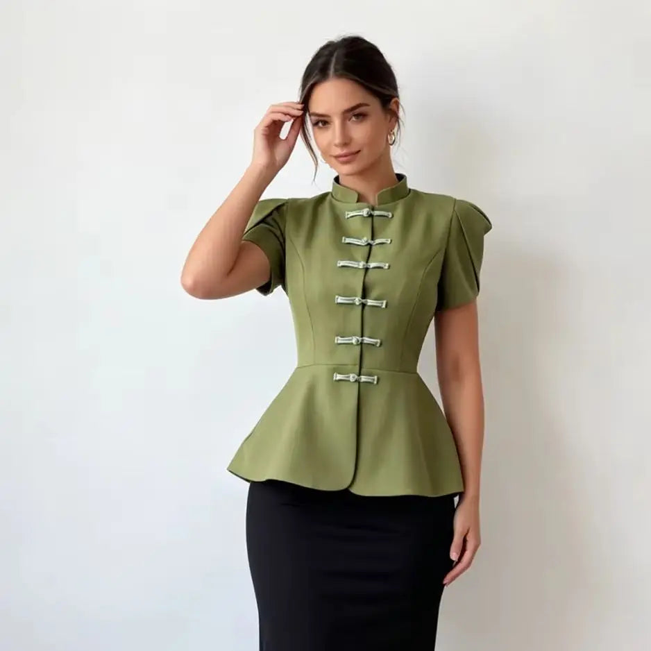 A woman modeling a short-sleeve olive green peplum top with decorative silver-tone frog closures and a black pencil skirt against a plain light background.