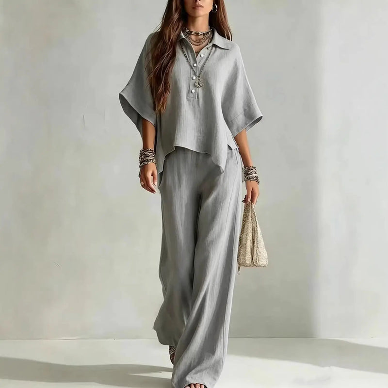 Woman wearing a gray outfit with wide-leg pants against a plain background