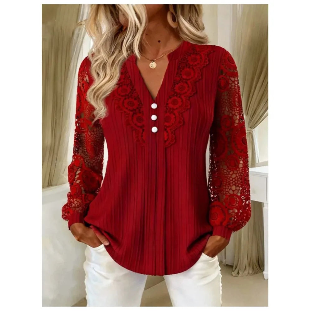 A woman wearing a red long-sleeve blouse with lace floral detailing on the shoulders and sleeves, white buttons down the front, and a V-neckline, paired with white pants.