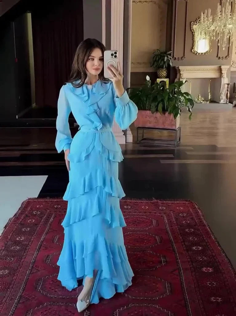 Woman taking a mirror selfie wearing a blue dress in an indoor setting.