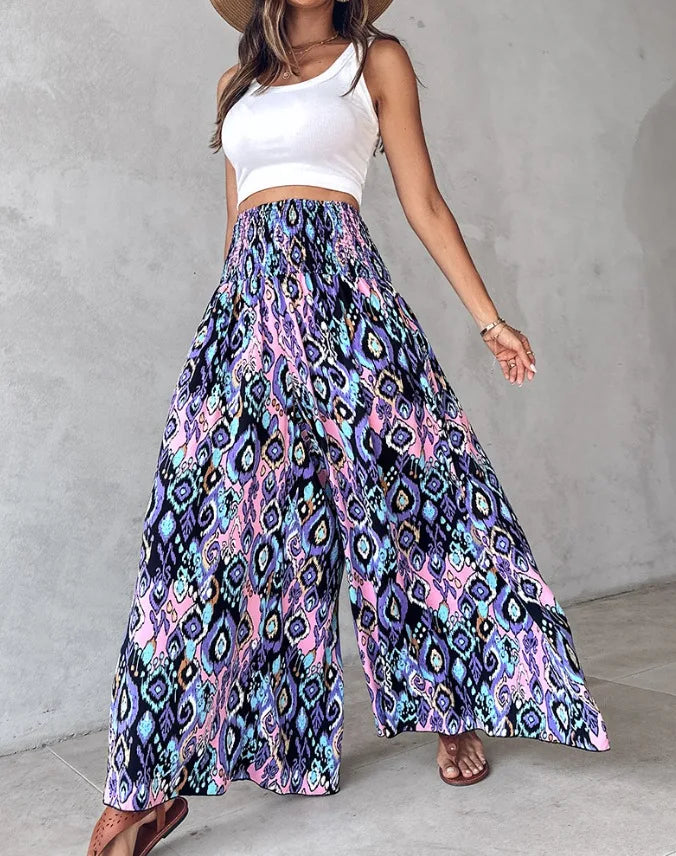 Woman wearing a white crop top and colorful patterned skirt against a gray concrete wall.