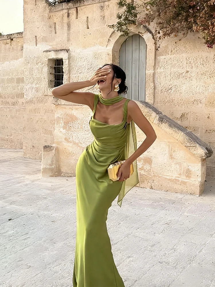 Woman in a green dress standing in front of a stone building.