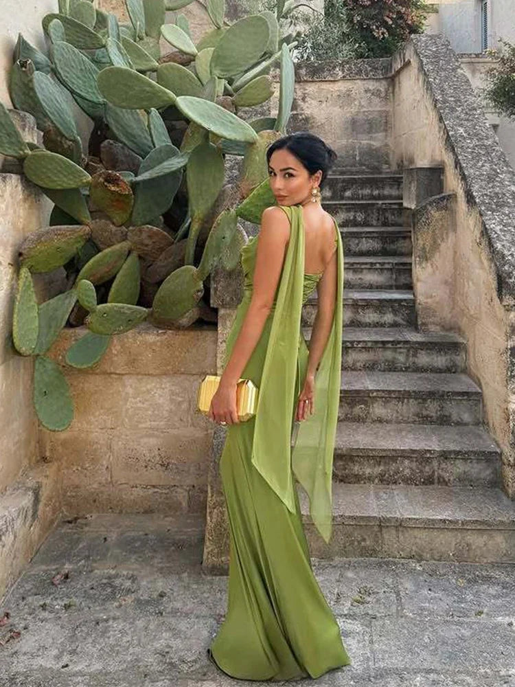 Woman in a green dress standing next to a cactus plant on a stone staircase.