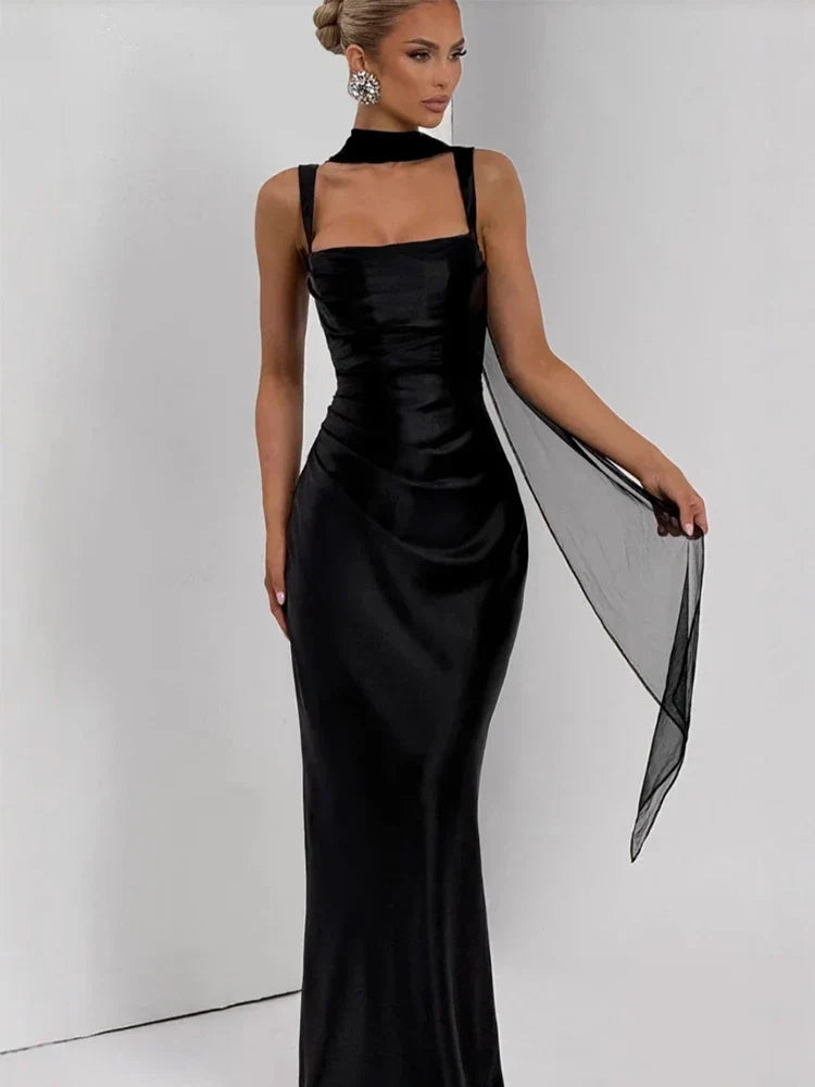 Woman wearing a black evening gown with sheer overlay on a white background