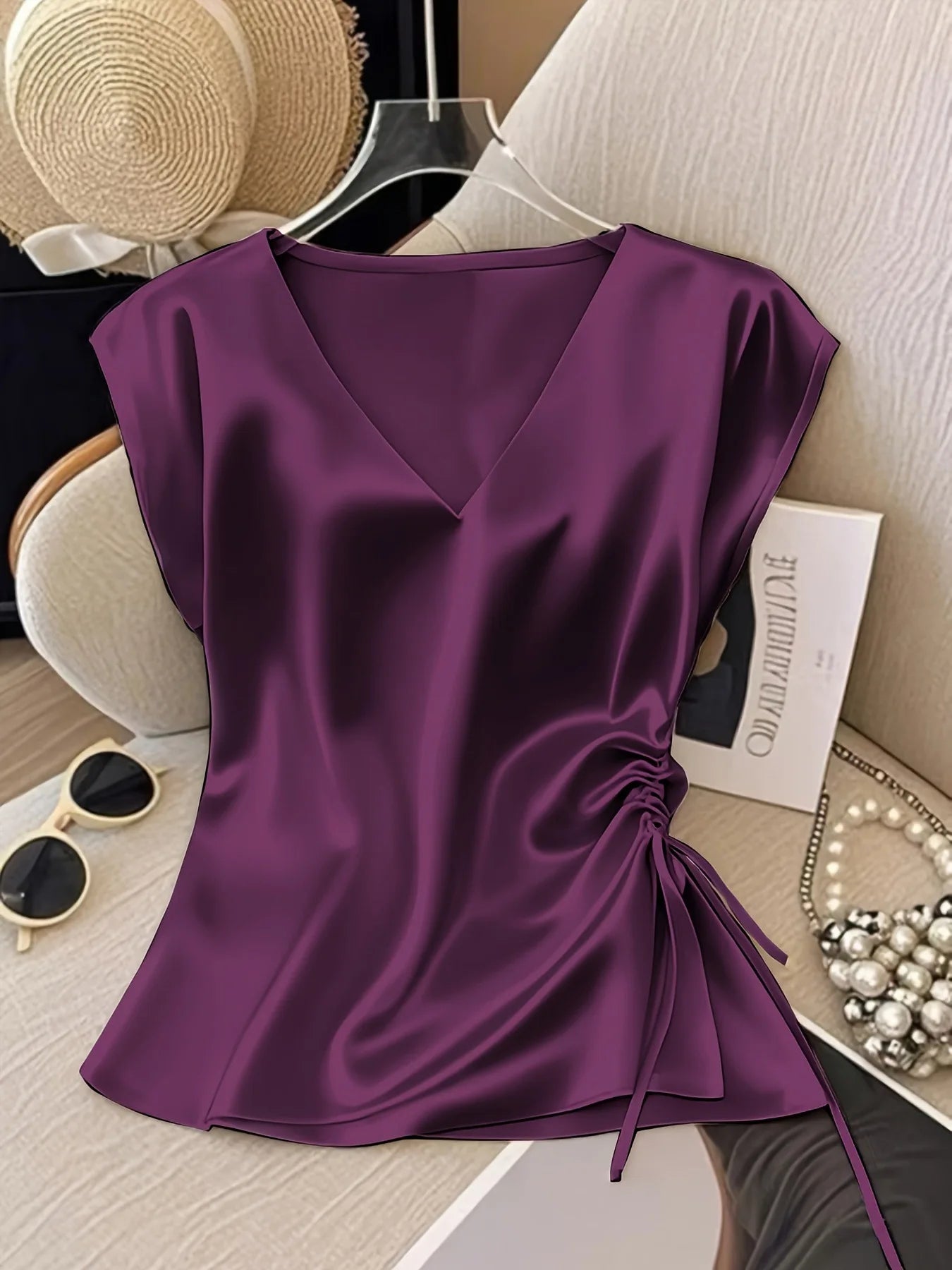Purple satin top on a chair with accessories in the background