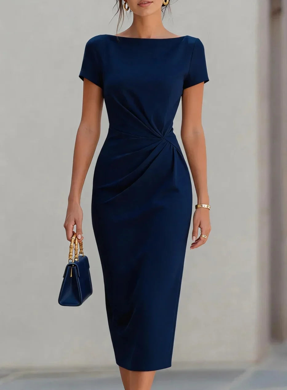 Woman wearing a navy blue dress holding a matching handbag against a neutral background
