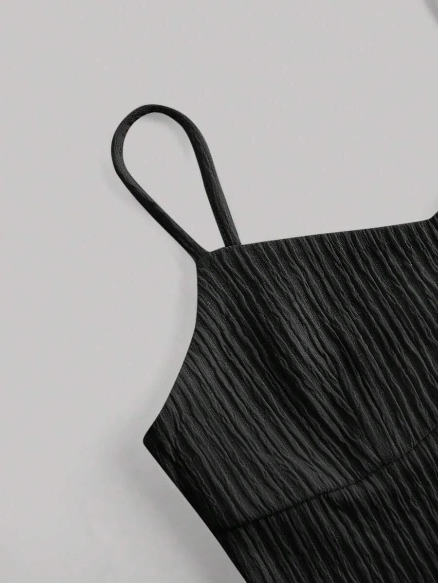 Black pleated dress with thin straps on a light gray background