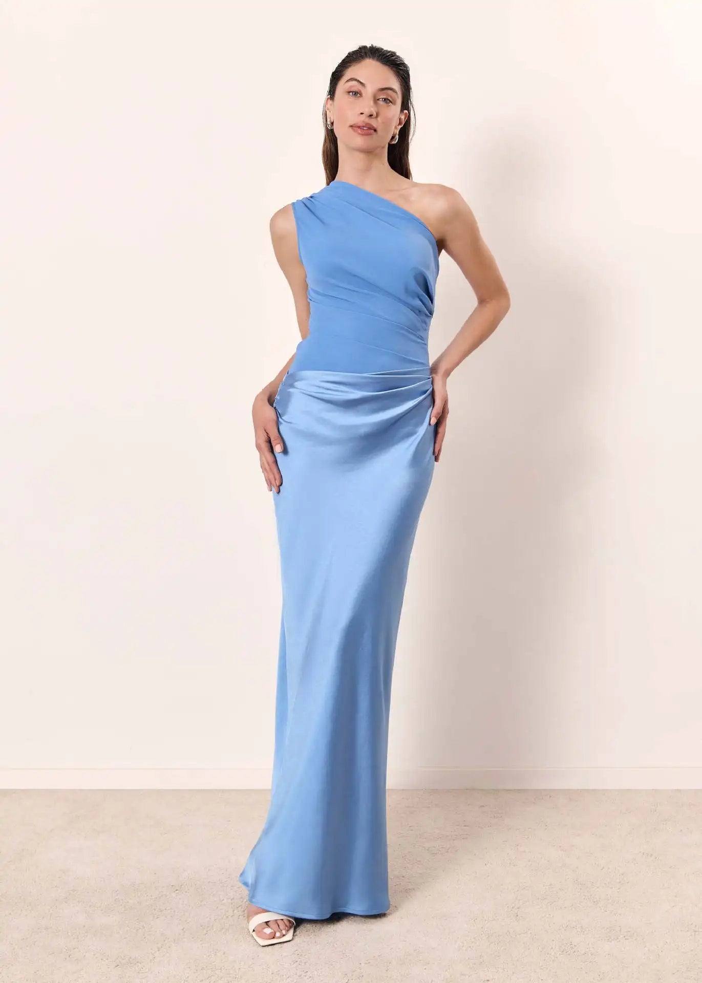Woman wearing a light blue one-shoulder dress against a white background