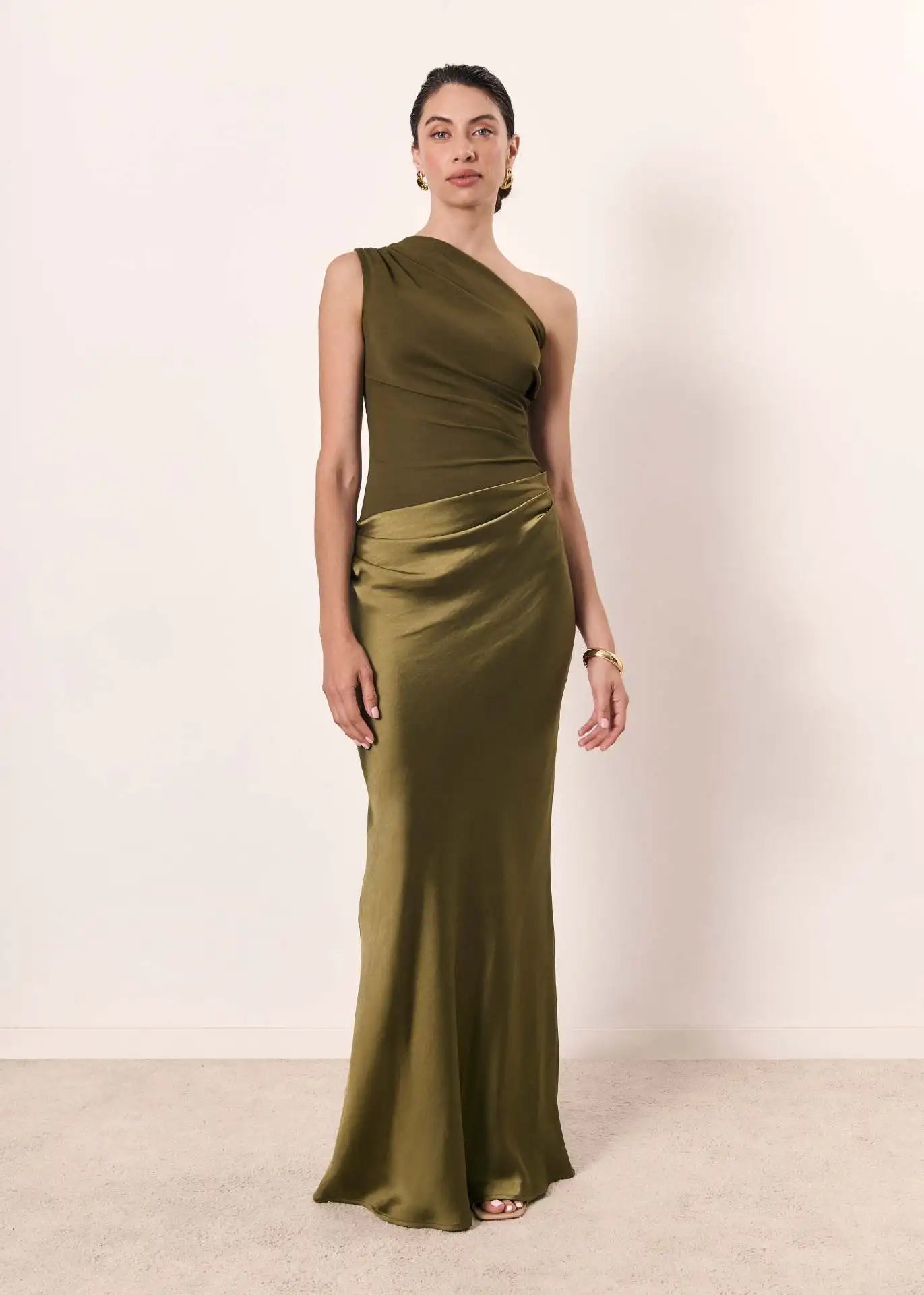 Woman wearing a green one-shoulder dress against a plain background