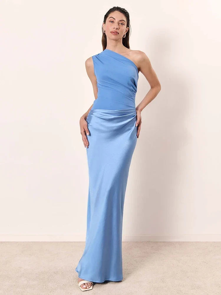 Woman wearing a light blue one-shoulder dress against a plain background