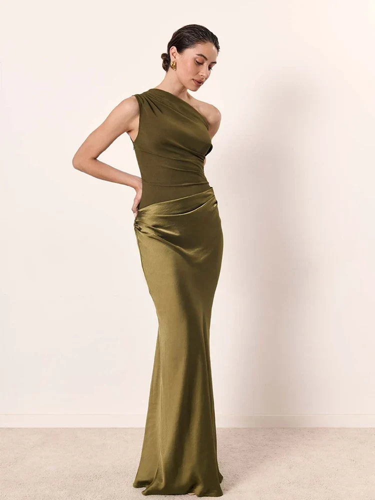 Woman wearing a green one-shoulder evening gown against a plain background