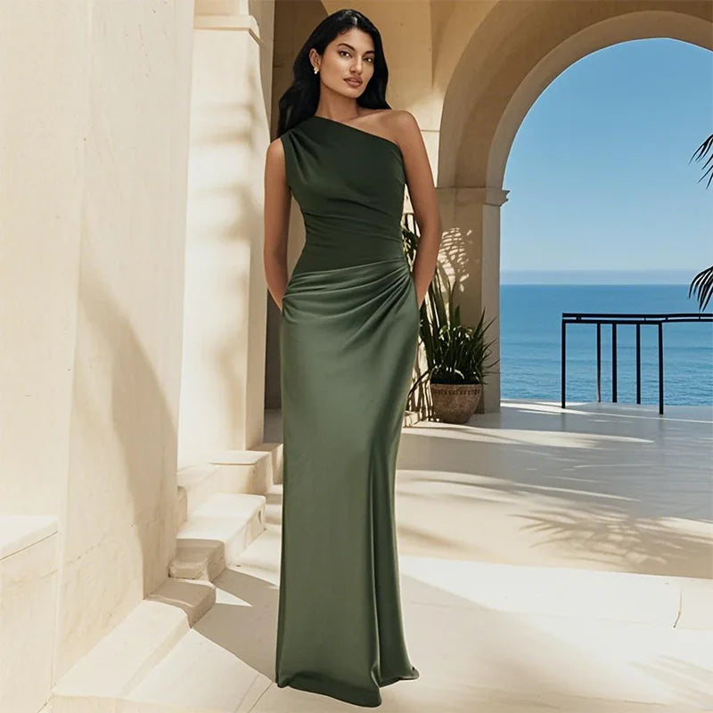 Woman in a green dress standing in a sunlit outdoor setting with ocean view